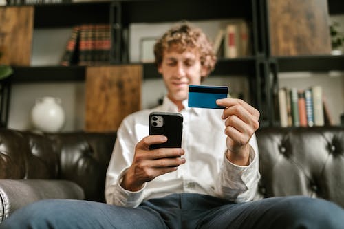 a person is holding a phone and a credit card. 