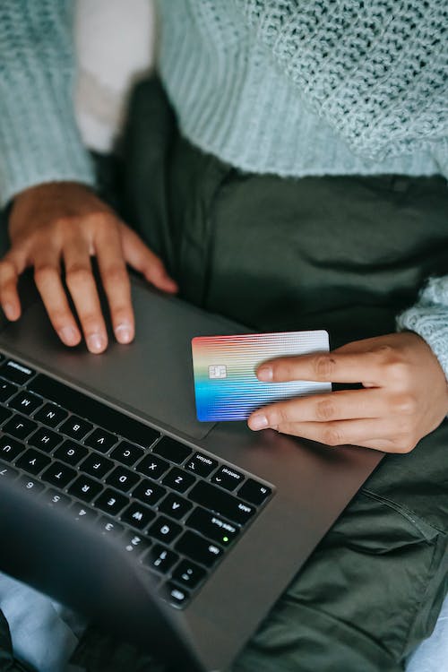 A person holding a credit card while using a laptop