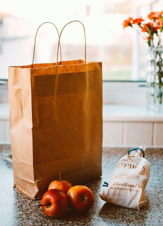 A paper bag next to apples and biscuits