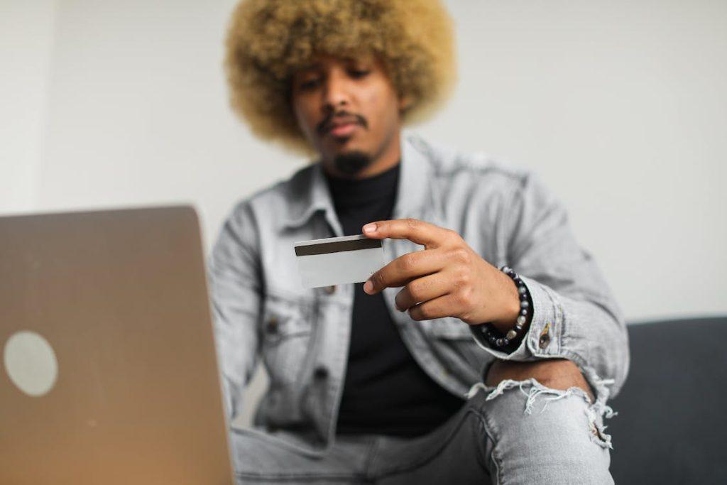 A person holding a credit card in front of a laptop