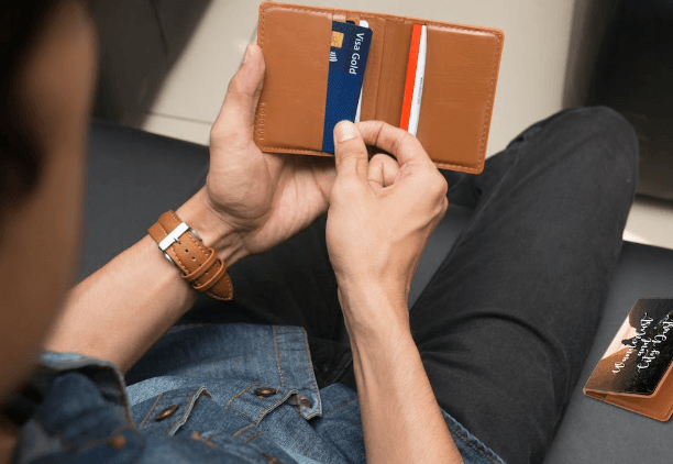 Person taking a card out of a brown cardholder.  