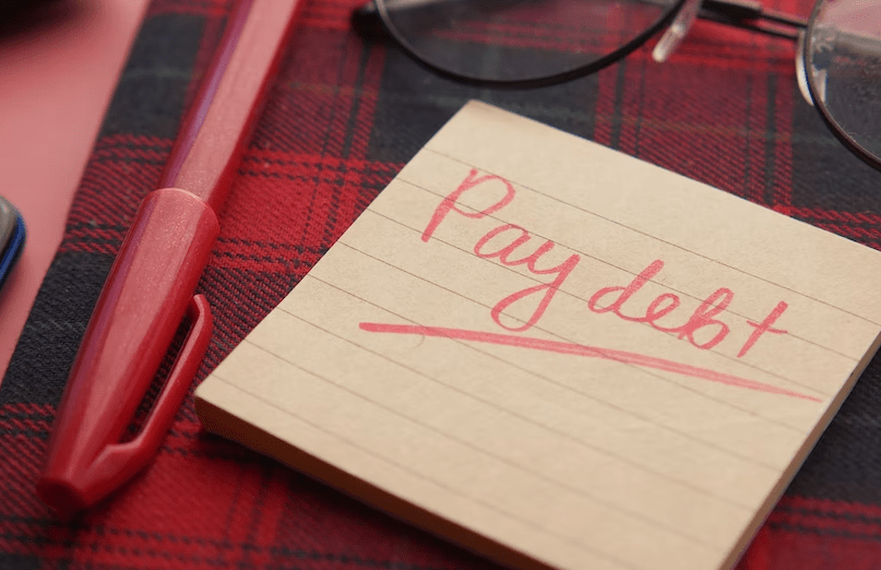 Post-it note saying “Pay debt”