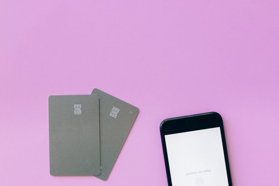 credit cards and a smartphone on a pink surface