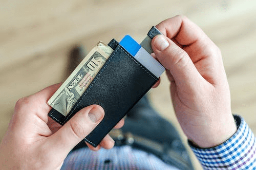 a person holding a wallet with credit cards and pulling one out