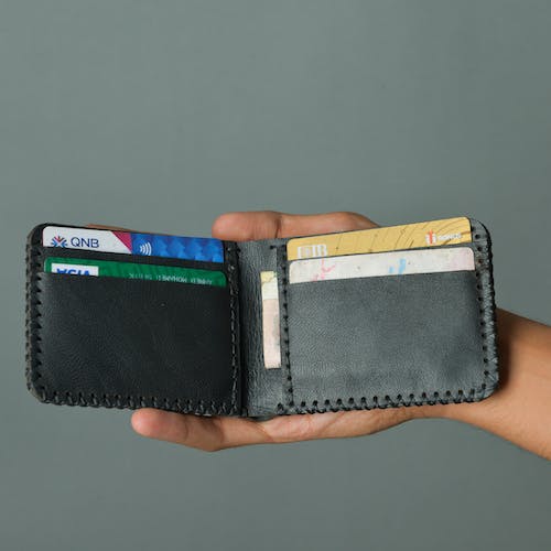 a person holding a wallet with several credit cards