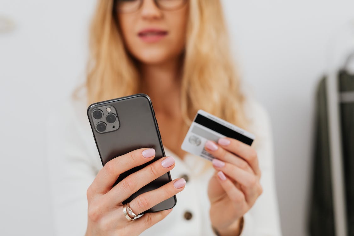 A woman holding a credit card and smartphone